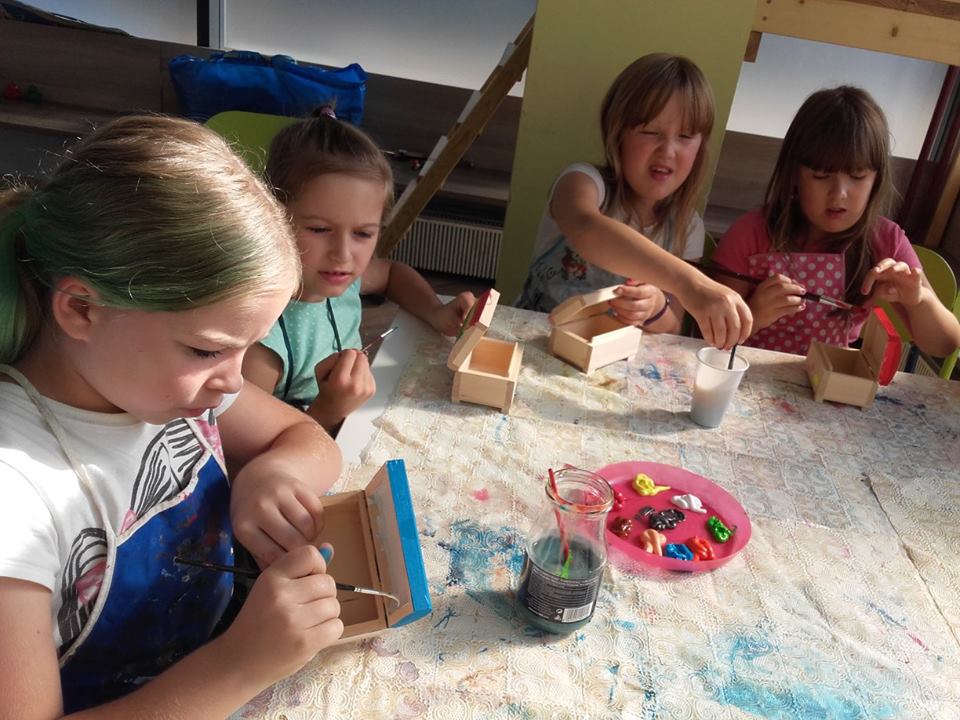 4 dziewczynki malują farbami drewniane szkatułki